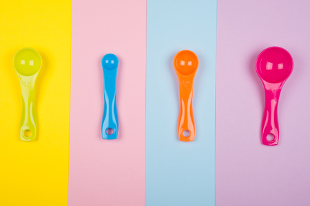 Set of colorful measuring spoons on a multicolored background (top view)の写真素材
