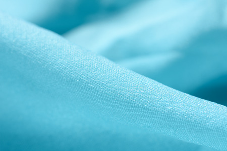 Extreme macro shot of folded turquoise fabric (as an abstract curved turquoise background), shallow DOF, selective focusの写真素材
