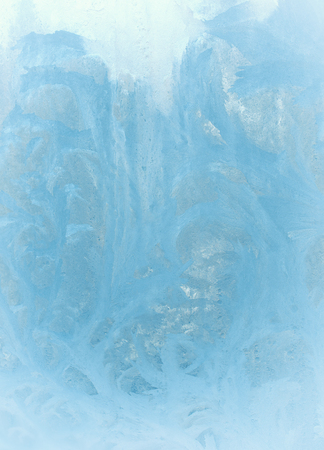 Fantastic fairy-like light blue frost pattern on the window glass (as an abstract winter background), retro tonedの写真素材