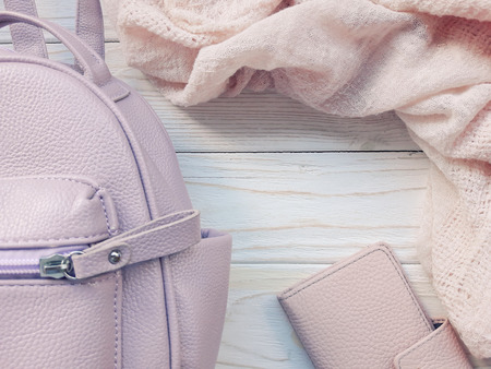 Top view of a pink backpack, pink wallet and pink scarf on a wooden background (retro toned), copy space in the center for your textの写真素材