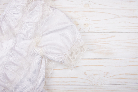 Closeup of a white communion or wedding dress against a white wooden background (top view, copy space on the right for your text)の写真素材