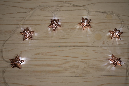 Garland with Christmas lights (in the shape of stars) on a wooden background, copy space in the...