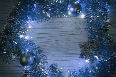 Garland with Christmas lights and Christmas decorations on a wooden background at night as the New Year or Christmas background in blue tones (selective focus), copy space in the center for your textの写真素材