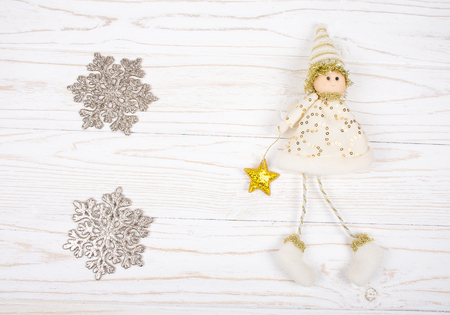 Two silver snowflakes and a cute toy Christmas elf on a white wooden background (isolated on white), top view, copy space in the center for your textの写真素材