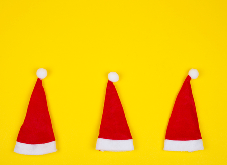 Three small Santa hats on the bright yellow background as the Christmas concept (top view, minimal style), copy space for your textの写真素材