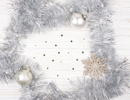 Christmas or New Year decorations (silver tinsel, garland with Christmas lights, snowflake and Christmas balls) on a wooden background, copy space in the centerの写真素材