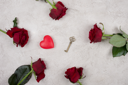 Five bright red roses, a heart and a key on a gray marble or concrete background (top view) as the Valentine day or love conceptの写真素材