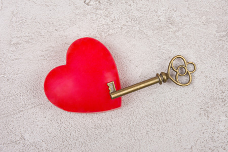 Bright red heart and an old antique key on a gray marble or concrete background (top view) as the Valentine day or love conceptの写真素材