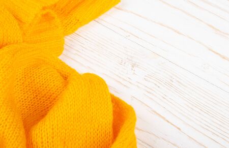 Closeup of bright yellow knitted wool on a white wooden backgroundの写真素材