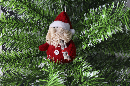 small red toy Santa Claus with music paper sitting in a Christmas treeの写真素材