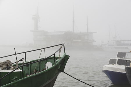 Morning fog in the seaport in Nida, Lithuania. Old green fishing baot.の写真素材