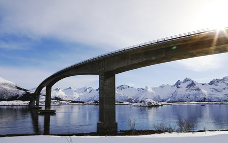 Bridge in the Lofoten islands in winter with lens flare.and mountains reflection.の写真素材
