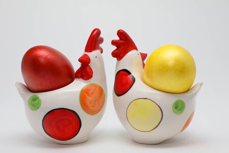 Colorful Easter eggs in two toy hens on white background, Spring Image. Easter concept.の写真素材