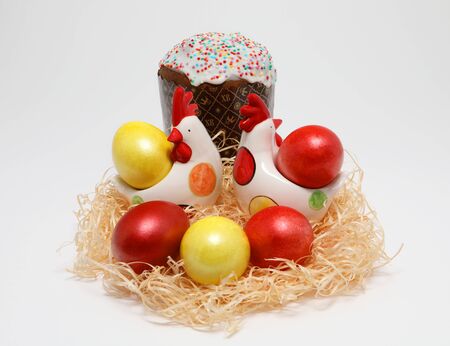 Colorful Easter eggs and two toy hens in a nest and Easter cake on white background, Spring Image. Easter concept.の写真素材