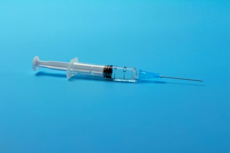 A syringe with a vaccine on  blueの写真素材