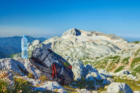 Hiking drinking, a bottle of water and a backpack on the top of the mountain