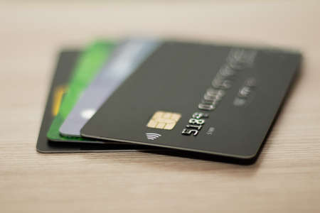 Credit card in black, green, and gray on a wooden background. Finance. Payments