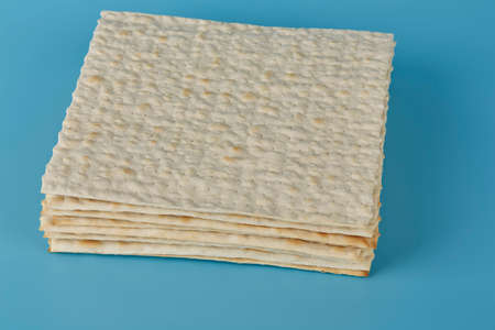 Traditional Jewish matzah for the holiday of Passover lies on a blue background with a stack of...