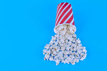 A glass of popcorn is turned from top to bottom. popcorn is poured out of the red glass. The concept...