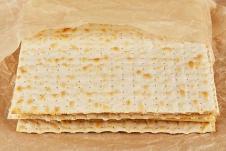 Jewish kosher matzah for the religious holiday of Passover on a wooden table wrapped in a yellow...