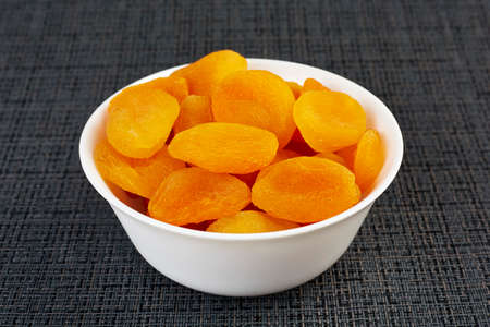 Dried apricots in a white plate on a black background. The concept of healthy eatingの写真素材