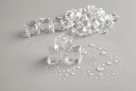 Broken ice cubes on a gray background with water dropletsの写真素材