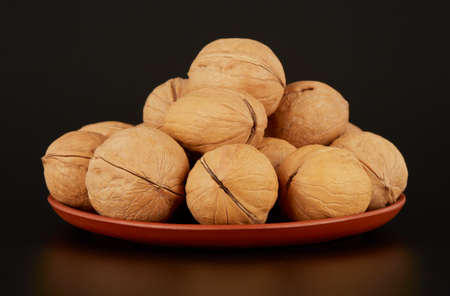 A mound of walnuts on a clay plate on a black backgroundの写真素材