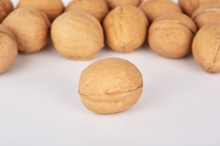 Many walnuts on a white background one nut lies separatelyの写真素材