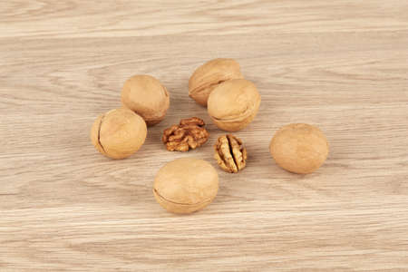 Whole walnuts on a wooden background together with peeled walnutsの写真素材