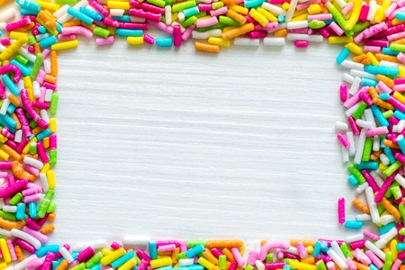 Sugar sprinkle dots, decoration for cake and bakery. Colored frame with wood texture insideの写真素材