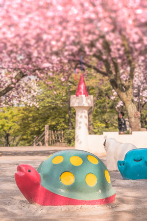 Cute red turtle and blue pig scuptures make a hanami party under the pink cherry blossom trees of Asukayama park in the Kita district of Tokyo, Japan.のeditorial素材