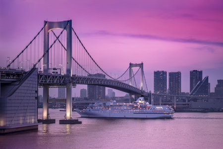 Venus cruise ship sailing in Odaiba Bay under the Rainbow Bridge in a pink sunset light.のeditorial素材