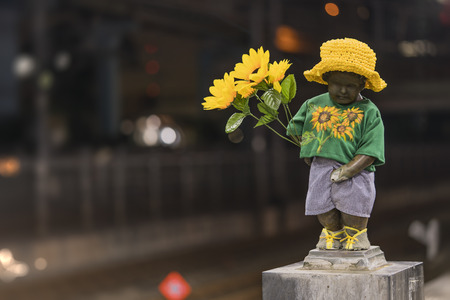 Close-up sculpture of a little boy Manneken pee peeing and holding sunflower flowers on the quay of hamamatsucho station in Tokyo, Japan.の写真素材