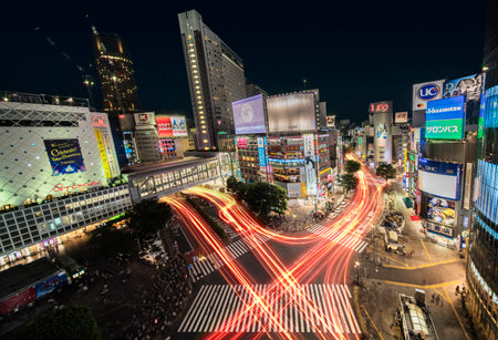 Aerial view of the Shibuya Crossing Intersection in front of Shibuya Station on a summer night with the speed lights flow of cars.のeditorial素材