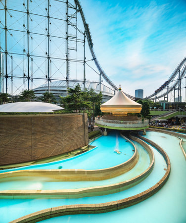Laqua Tokyo Dome City Mall with its impressive roller coaster integrated in the gallery of its shopping center with a carousel  and water coaster under the summer blue sky.のeditorial素材