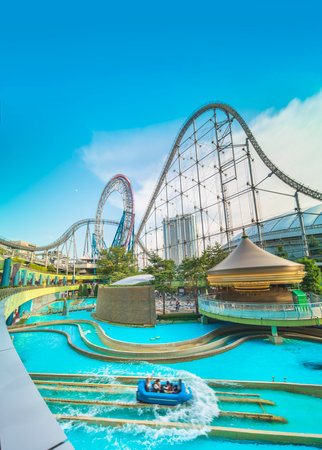 Laqua Tokyo Dome City Mall with its impressive roller coaster integrated in the gallery of its shopping center with a carousel  and water coaster under the summer blue sky.のeditorial素材