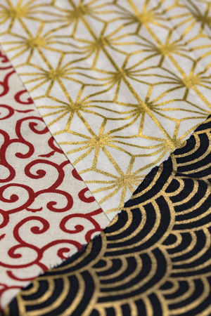 Highly detailed all over background texture of traditionals japaneses red, gold and white and black hemp leaves or rainbow  shaped pattern design textile in synthetic fabric.の写真素材