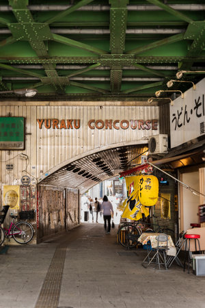 Underpass Yurakucho Concourse under the railway line of the station Yurakucho. Japanese noodle stalls and sake bars revive the nostalgic years of Showa air with old posters and placards glued to the walls of the tunnel.のeditorial素材