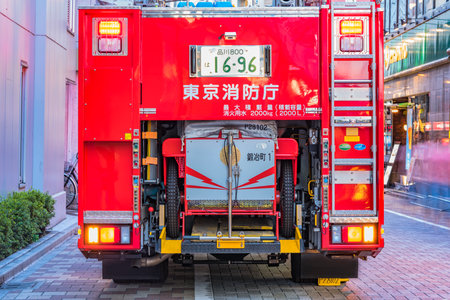 Rear view of a red Japanese fire truck with its lit traffic lights and license plate registered in...