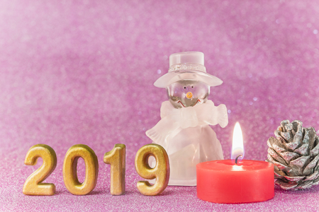 Pink glitter background for New Year's Cards with a snowman figurine, a Christmascamdle, a bread apple and handmade golden numbers of 2019 year.の写真素材