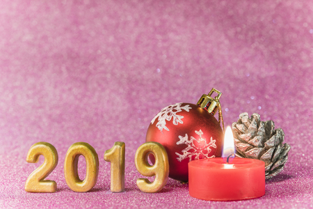 Pink glitter background for New Year's Cards with Christmas tree ball and silver bread apple around a candle and handmade golden numbers of 2019 year.の写真素材