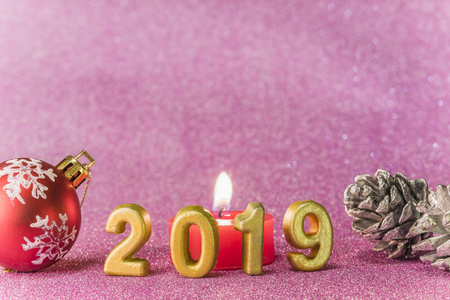 Pink glitter background for New Year's Cards with Christmas tree ball and silver bread apple around a candle and handmade golden numbers of 2019 year.の写真素材