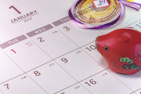Japanese New Year's ornament with ideograms Geishun which means Welcoming Spring with cute Japanese Zodiac animal figurines of boar and Japanese calendar open on 2019 January page.の写真素材
