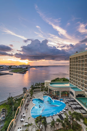 Naha, Japan - September 17, 2018: Sunset over the butterfly-shaped swimming pool of Leisure Hotel and the sea of Sumiyoshi district of Naha City in Okinawa island.のeditorial素材