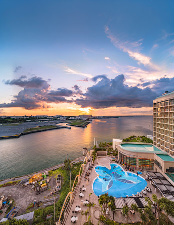 Naha, Japan - September 17, 2018: Sunset over the butterfly-shaped swimming pool of Leisure Hotel and the sea of Sumiyoshi district of Naha City in Okinawa island.のeditorial素材