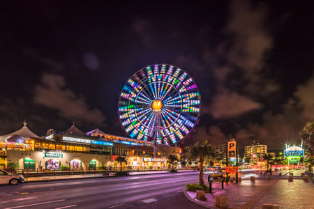 Naha, Japan - September 16, 2018: Night view of the Mihama Carnival Park Ferris wheel located in the American Village neighborhood of Naha City decorated with palm trees near Sunset Beach in Okinawa.のeditorial素材