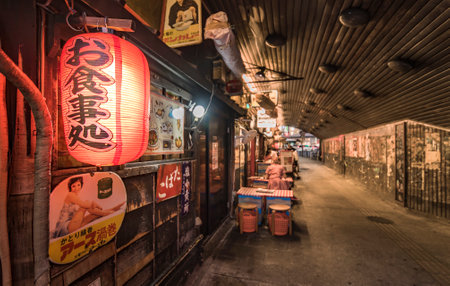 Night view of the Yuraku Concourse underpass under the railway line of the station Yurakucho. Japanese noodle stalls and sake bars revive the nostalgic years of Showa air with old posters and placards glued to the walls of the tunnel.のeditorial素材