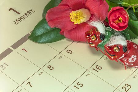 Japanese greeting card with Tsubaki flower called also the rose of winter and cute Japanese Folklore animals figurines of two lions Shishimai on a Japanese calendar open on January page.の写真素材