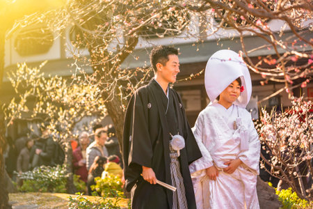 tokyo, japan - march 02 2020: Traditional Japanese shinto wedding of a couple in black haori kimono for men and white shiromuku for women under the plum trees in bloom at Tokyo's Yushima Tenmangu shrine.のeditorial素材