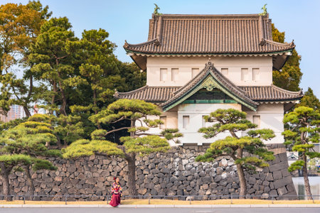 Japanese woman in hakama kimono in front of the huge donjon Edoj? sakurada tatsumiyagura with moats lined with pine trees outside of the Tokyo Imperial Palace.のeditorial素材